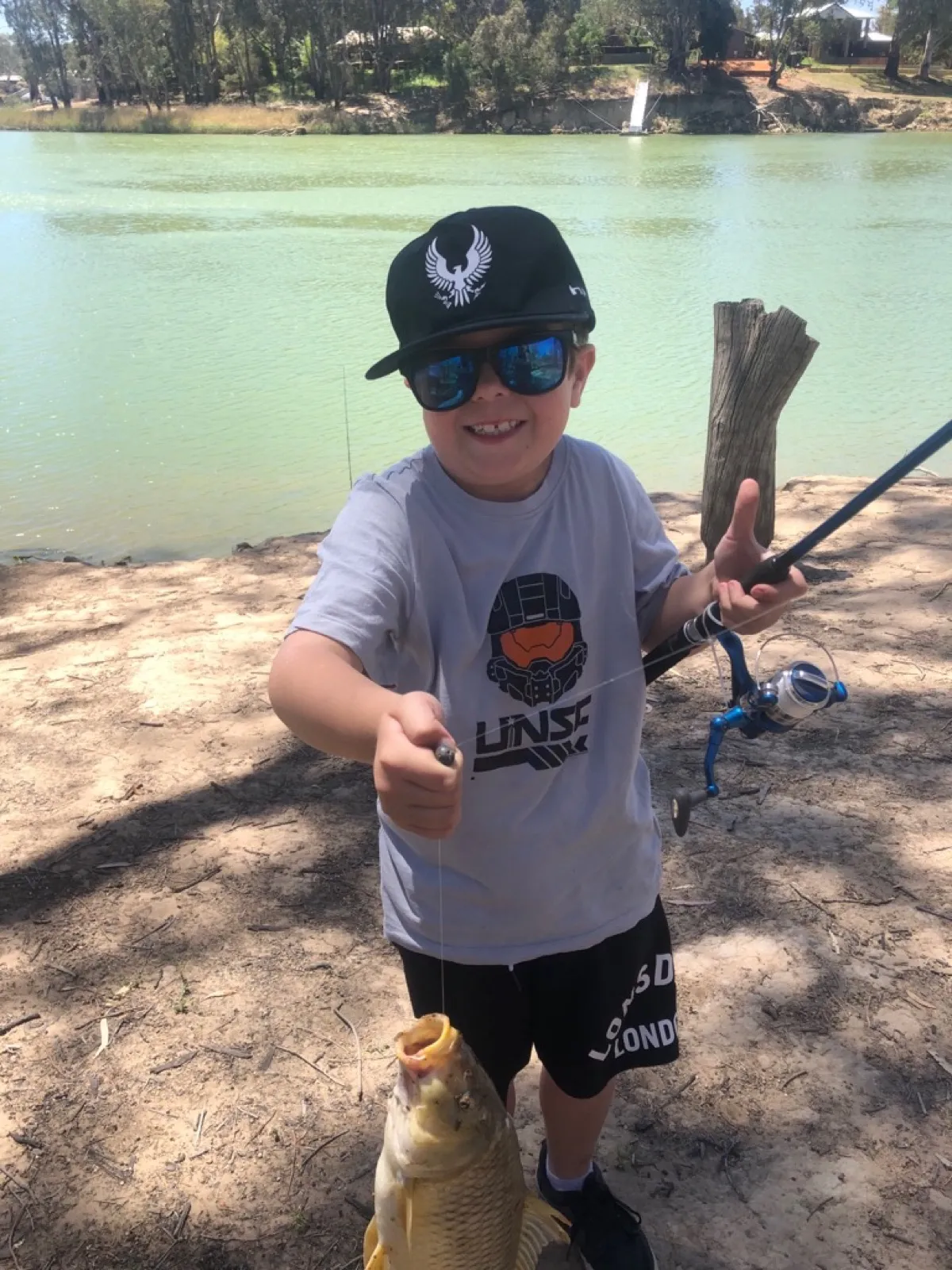 A child proudly holding their first fish of the season by the river